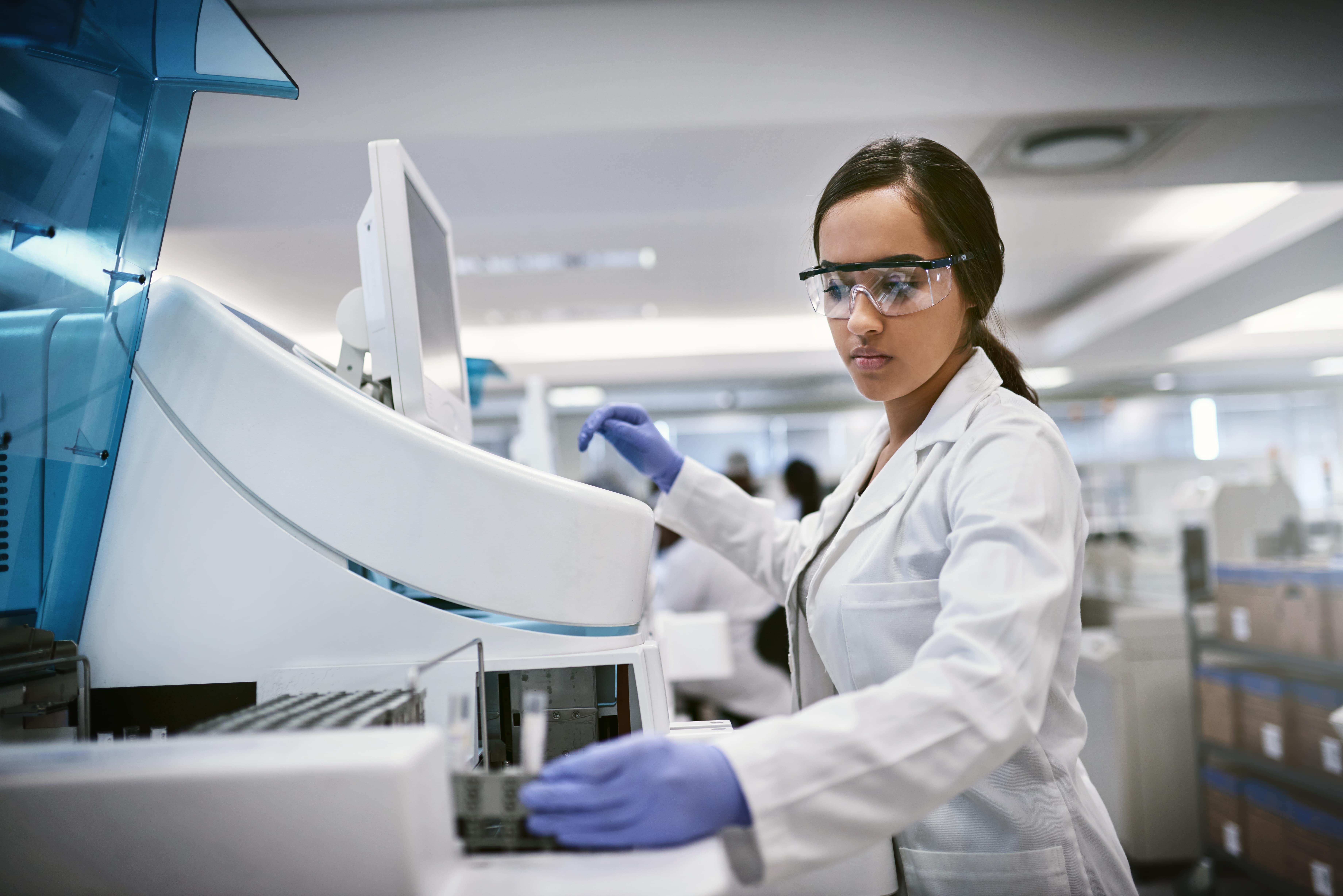 Scientifique en blouse de laboratoire qui effectue une recherche dans un laboratoire en utilisant une machine et de l’équipement de laboratoire