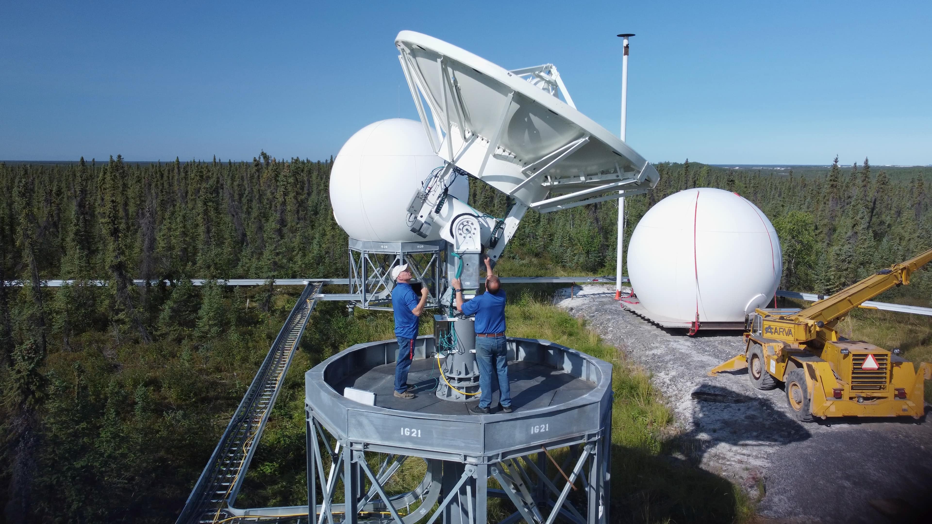 Des ouvriers ajustent les satellites à la station terrestre canadienne pour satellites à Inuvik (Territoires du Nord-Ouest)